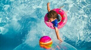 Enfant dans une piscine avec bouée et ballon