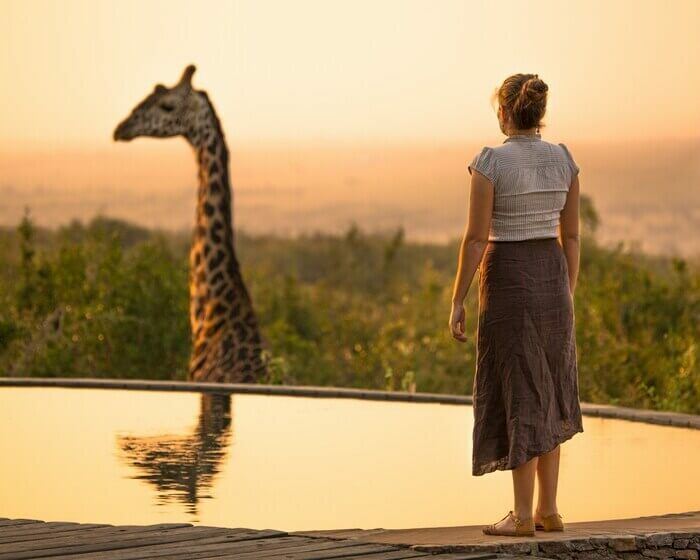Femme devant une piscine et une girafe