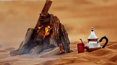 Feu de bois et théière dans le sable du désert