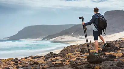 Homme en tenue de randonnée devant la mer