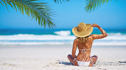 Femme assise sur la plage de dos