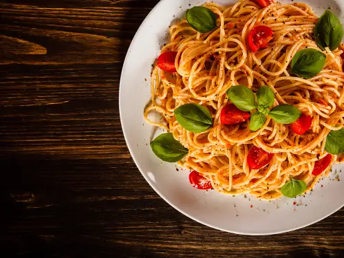 Assiette de spaghettis avec feuilles de basilic et tomates cerise