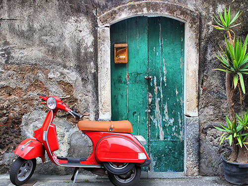 vespa rouge devant une porte verte