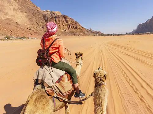 Femme en balade à dos de chameau dans le désert
