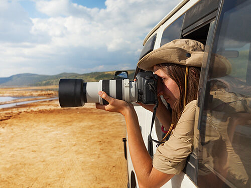 Femme avec appareil photo dans une jeep lors d'un safari