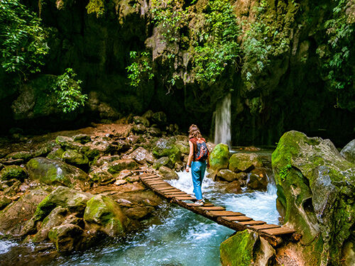 Femme sur un pont en bois devant une cascade