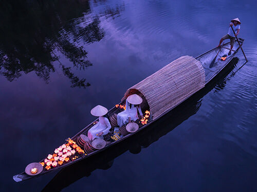 Femme sur une barque entourée de lanternes éclairées
