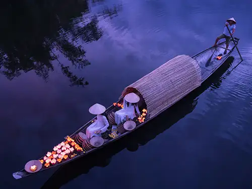 Femme sur une barque entourée de lanternes éclairées