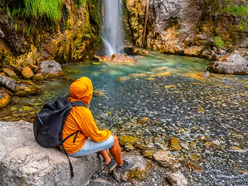 Homme assis devant une cascade
