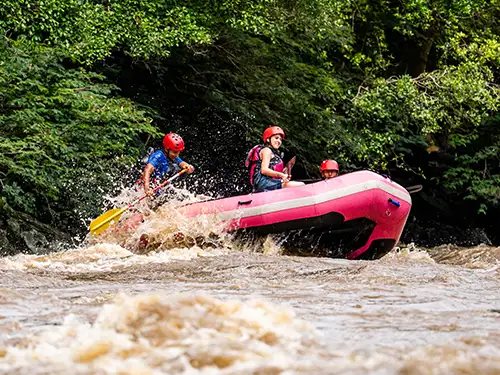 3 personnes avec casques en rafting