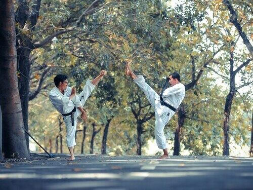 2 hommes font du taekwondo en extérieur