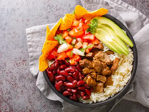 Assiette avec riz, légumes, haricots rouge : le Chifrijo