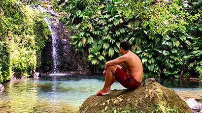 Homme assis sur un rocher devant une cascade