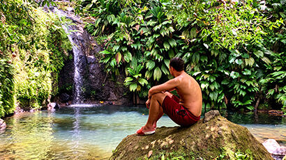 Homme assis sur un rocher devant une cascade