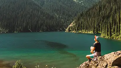 Homme assis au bord d'un lac