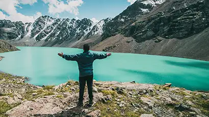 Homme de dos devant un lac turquoise