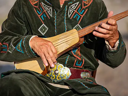 Homme qui jour du komuz (instrument de musique)