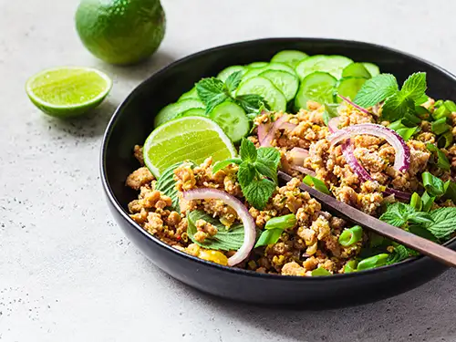 Assiette avec viande, citron vert et concombre, le laap