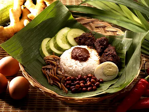 Plat dans un panier avec feuilles de bananier, riz, viande, concombre et oeuf