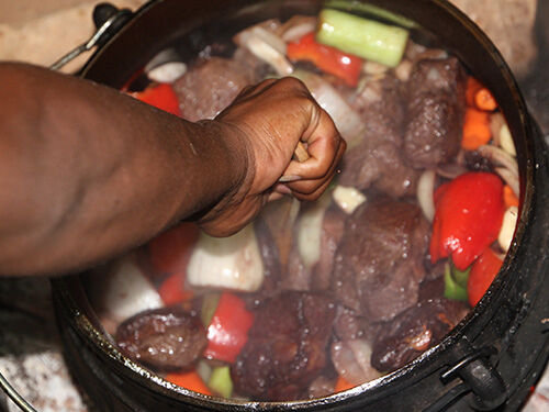 Main qui mélange un plat de viande et poivrons