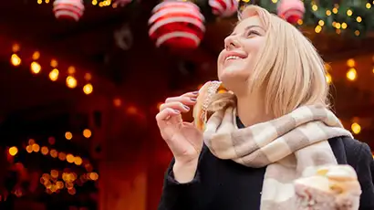 Femme qui mange une brioche au marché de Noël
