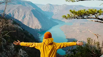 Homme avec un coupe-vent jaune devant des montagnes