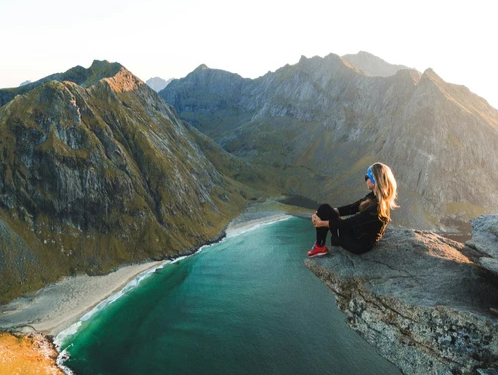Femme assise sur la pointe d'un rocher en hauteur