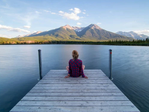 Femme assise de dos sur un ponton en bois